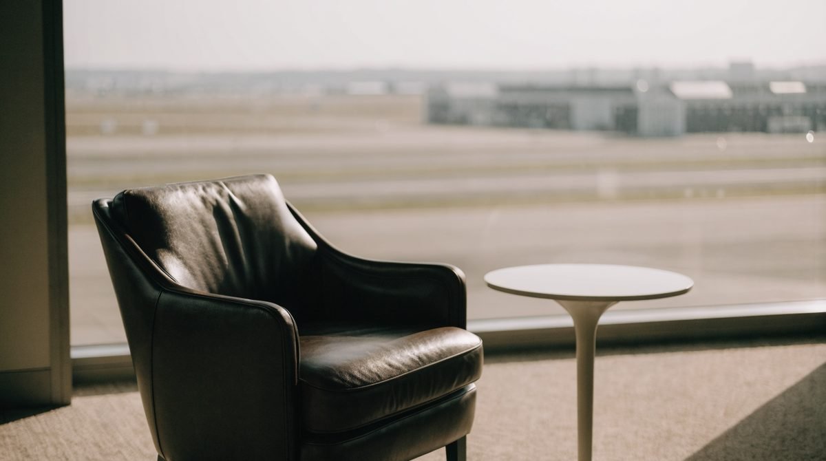 Poltrona de couro em sala VIP de aeroporto com janela ampla e vista para a pista ao amanhecer